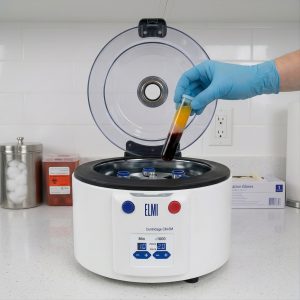 ELMI CM-6M PRP centrifuge with the lid open and a spun PRP separator tube being loaded into the 7M.08 flat-bottom rotor.